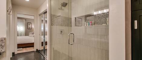 Un baño moderno con cabina de ducha de vidrio, inodoro a la vista y suelo de baldosas.