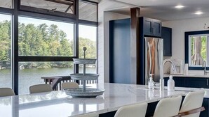Une cuisine moderne dotée d’un grand îlot central, de tabourets de bar et offrant une vue sur un lac.