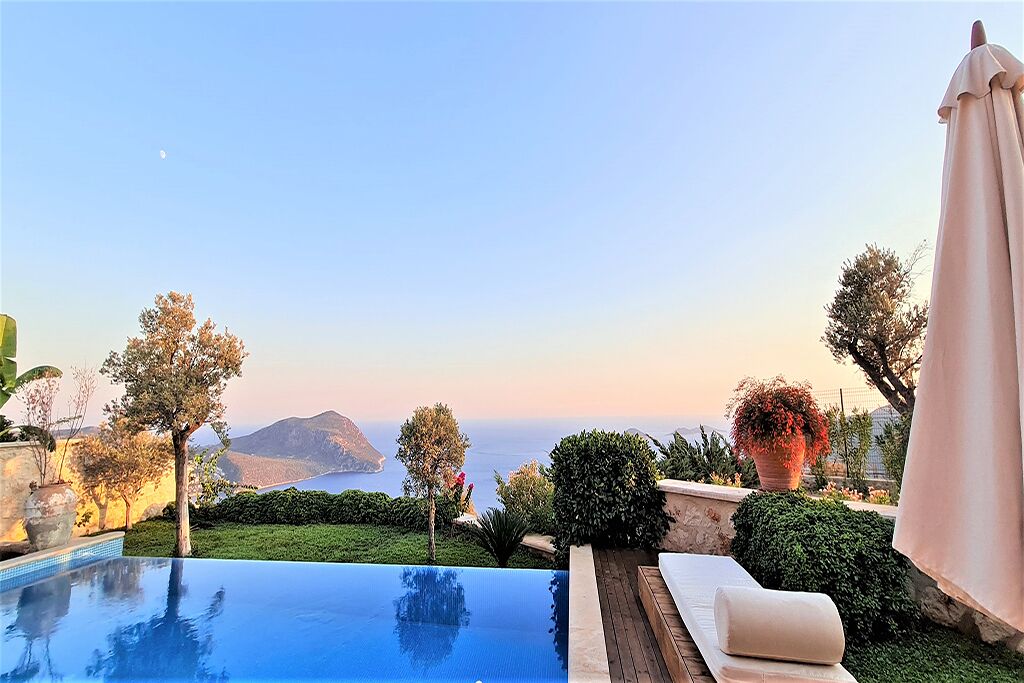 Une piscine à débordement offrant une vue sur la mer et les montagnes.