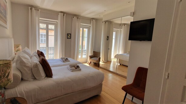 Una camera d'albergo con un letto, una sedia, una televisione e una finestra con tende.