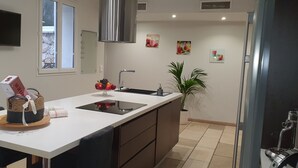 Una cucina moderna con un piano di lavoro bianco, elettrodomestici in acciaio inossidabile e una pianta in vaso.
