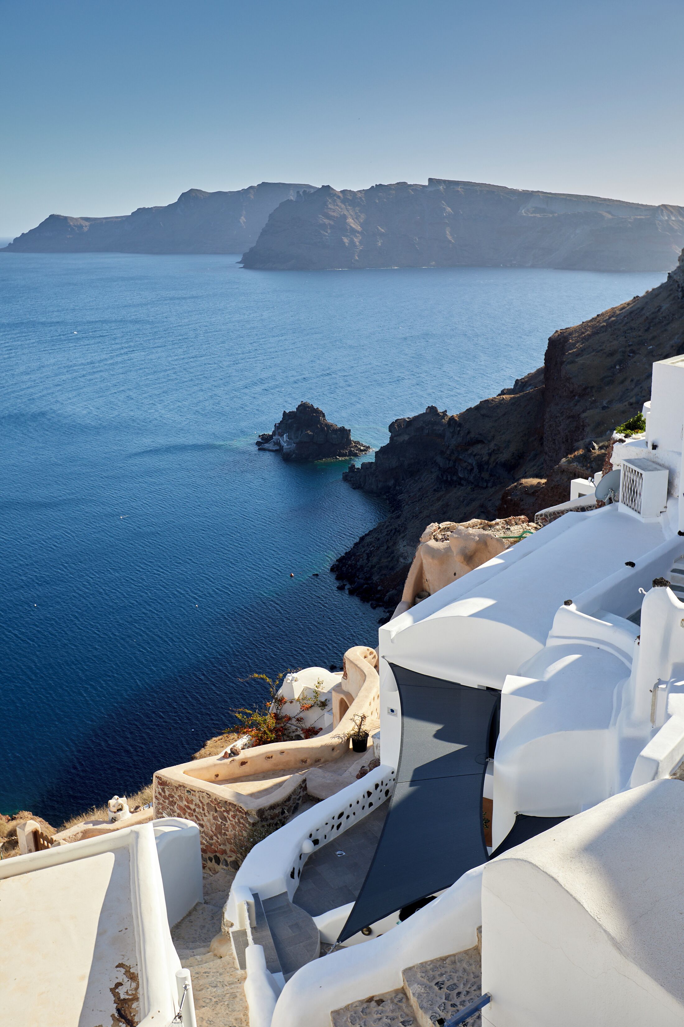 A seaside view with white buildings, a rocky coastline, and clear blue sea.