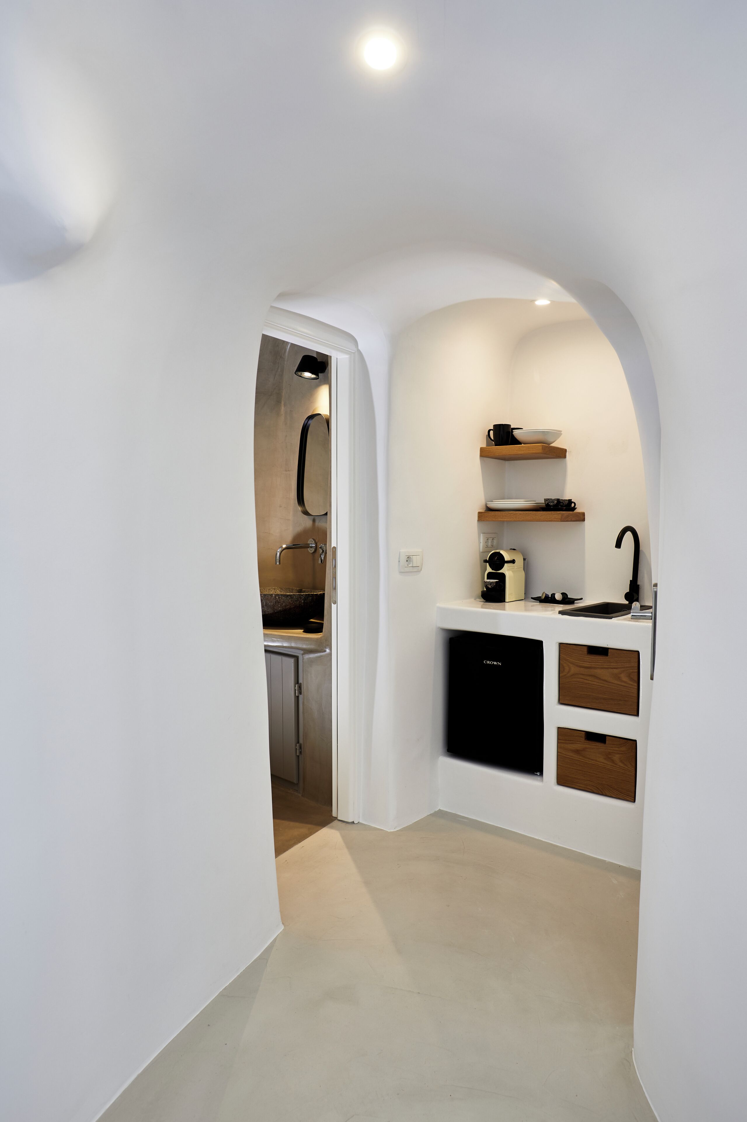 Una cocina compacta con paredes blancas, encimera de madera y lavavajillas negro.