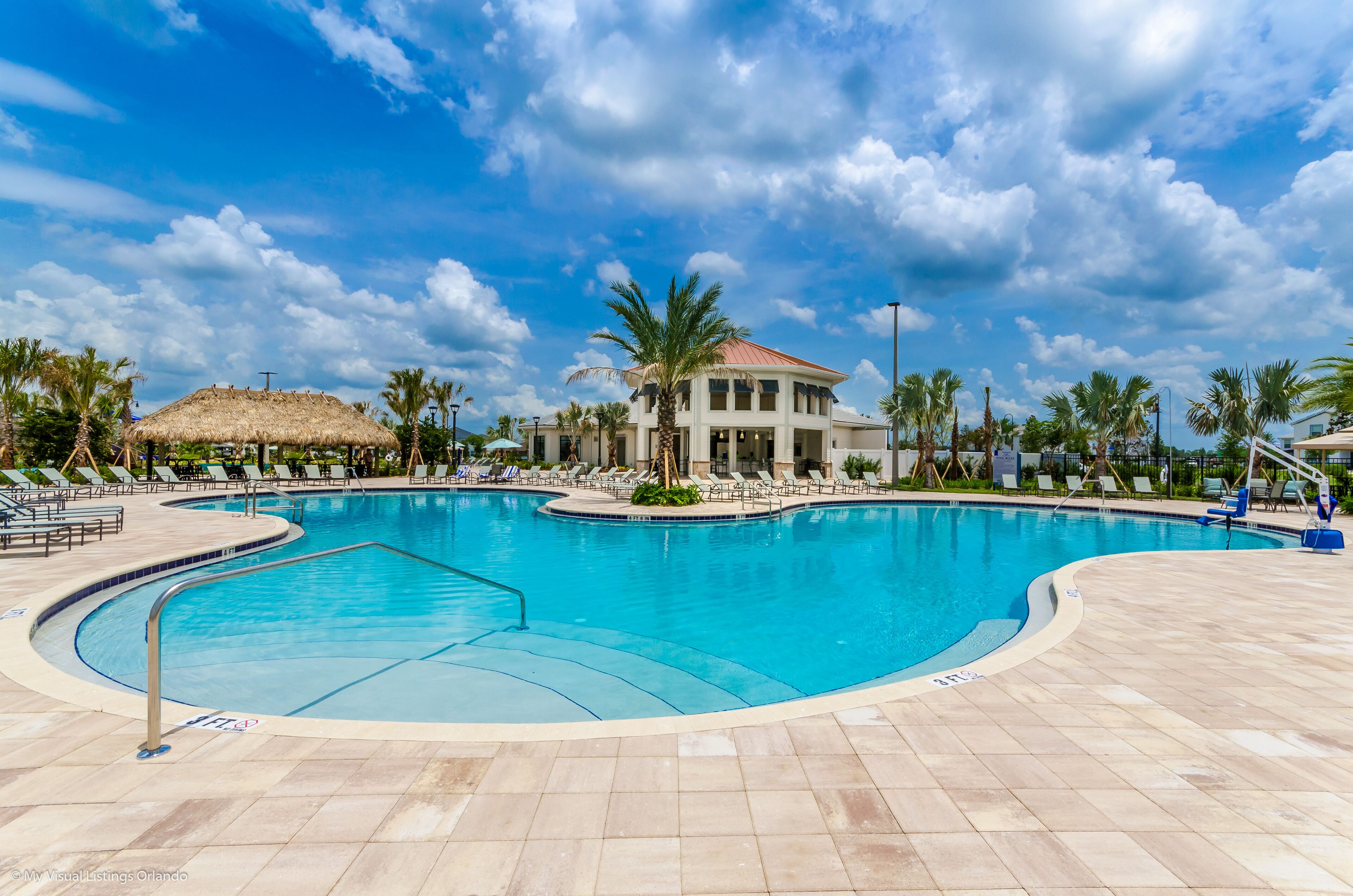 A swimming pool with lounge chairs and palm trees.
