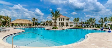 A swimming pool with lounge chairs and palm trees.