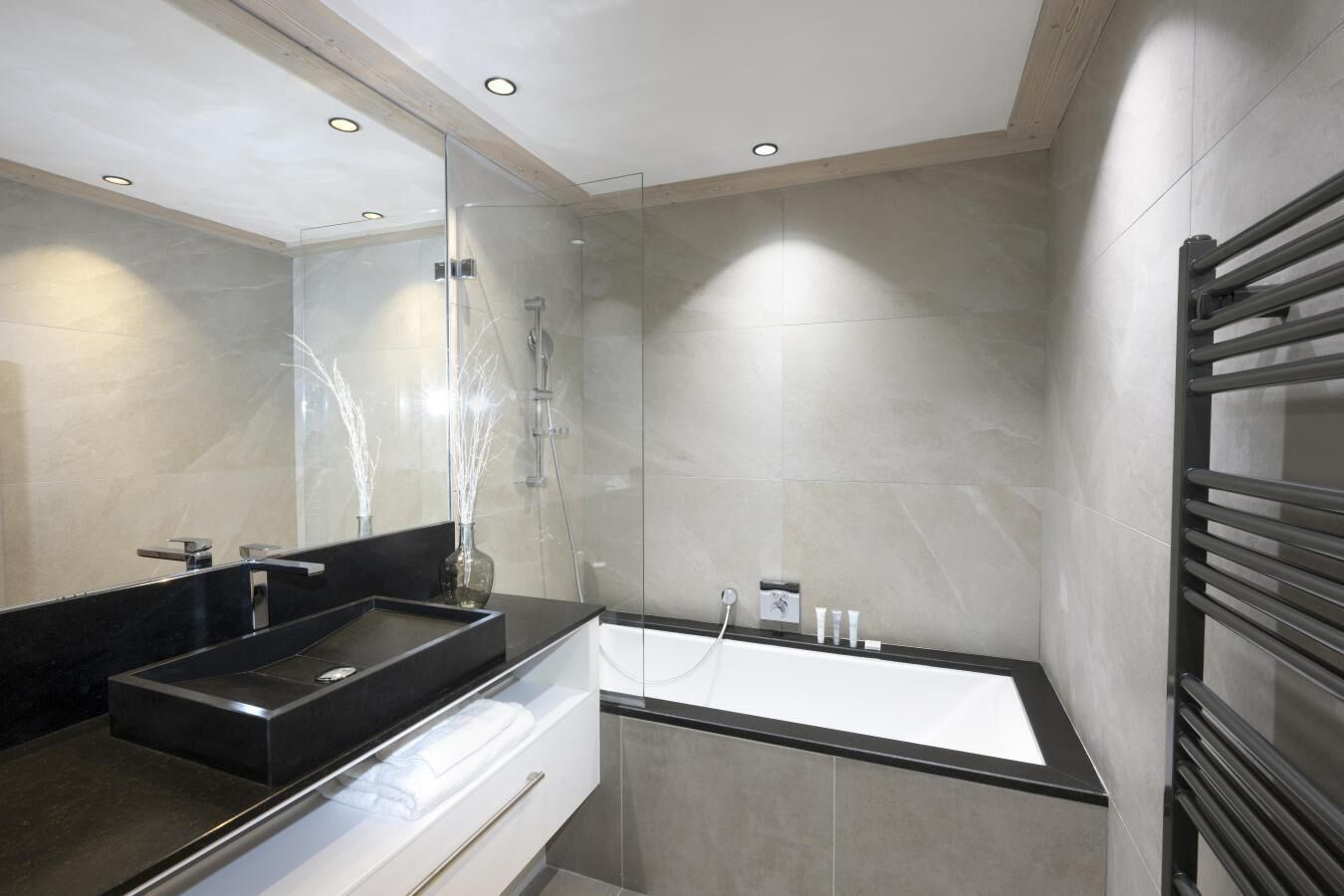 Une salle de bain moderne avec un lavabo noir, une douche en verre et une baignoire blanche.