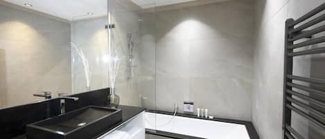 Une salle de bain moderne avec un lavabo noir, une douche en verre et une baignoire blanche.