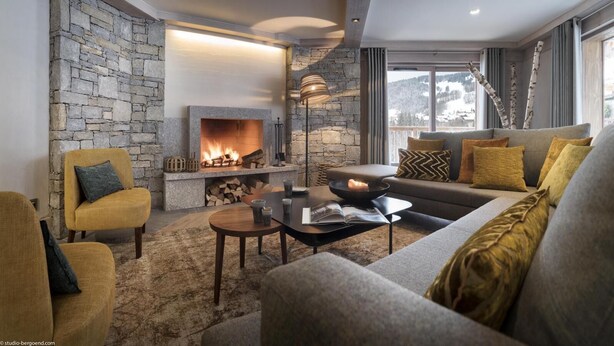 A cozy living room with a stone fireplace, comfortable seating, and a view of the outdoors. - Wifi, 100m from resort center, view mountain, fitness, swimming pool, sauna, hammam, balcony, tv (Le Grand-Bornand)