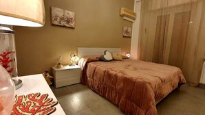 A bedroom with a bed, bedside table, lamp, and wall decorations. - Rosa Apartament (Palermo)