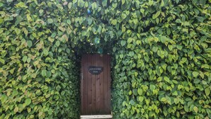 Eine Holztür mit der Aufschrift 'LOVESOME POD', umgeben von dichtem Grün.