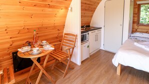 Eine gemütliche Holzhütte mit Essbereich, Küchenzeile und einem Bett.