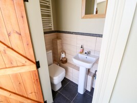 Un baño con inodoro, lavamanos y puerta de madera.
