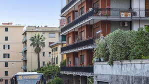 A multi-story residential building with balconies, some with plants.