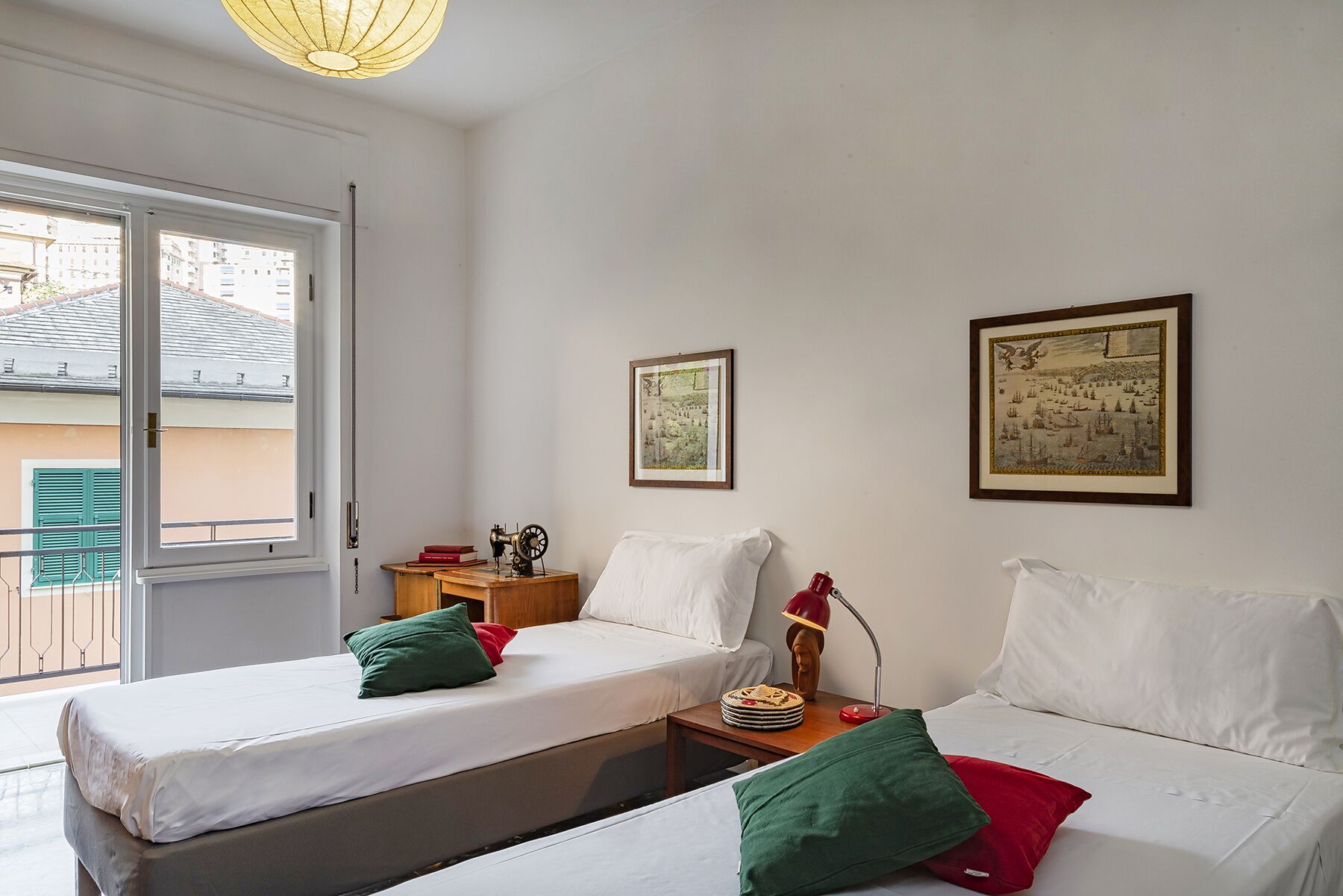 A room with two beds, a wooden nightstand, a sewing machine, and framed pictures on the wall.