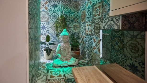 Ett område avsett för meditation med en staty, mönstrade plattor och en träbänk.