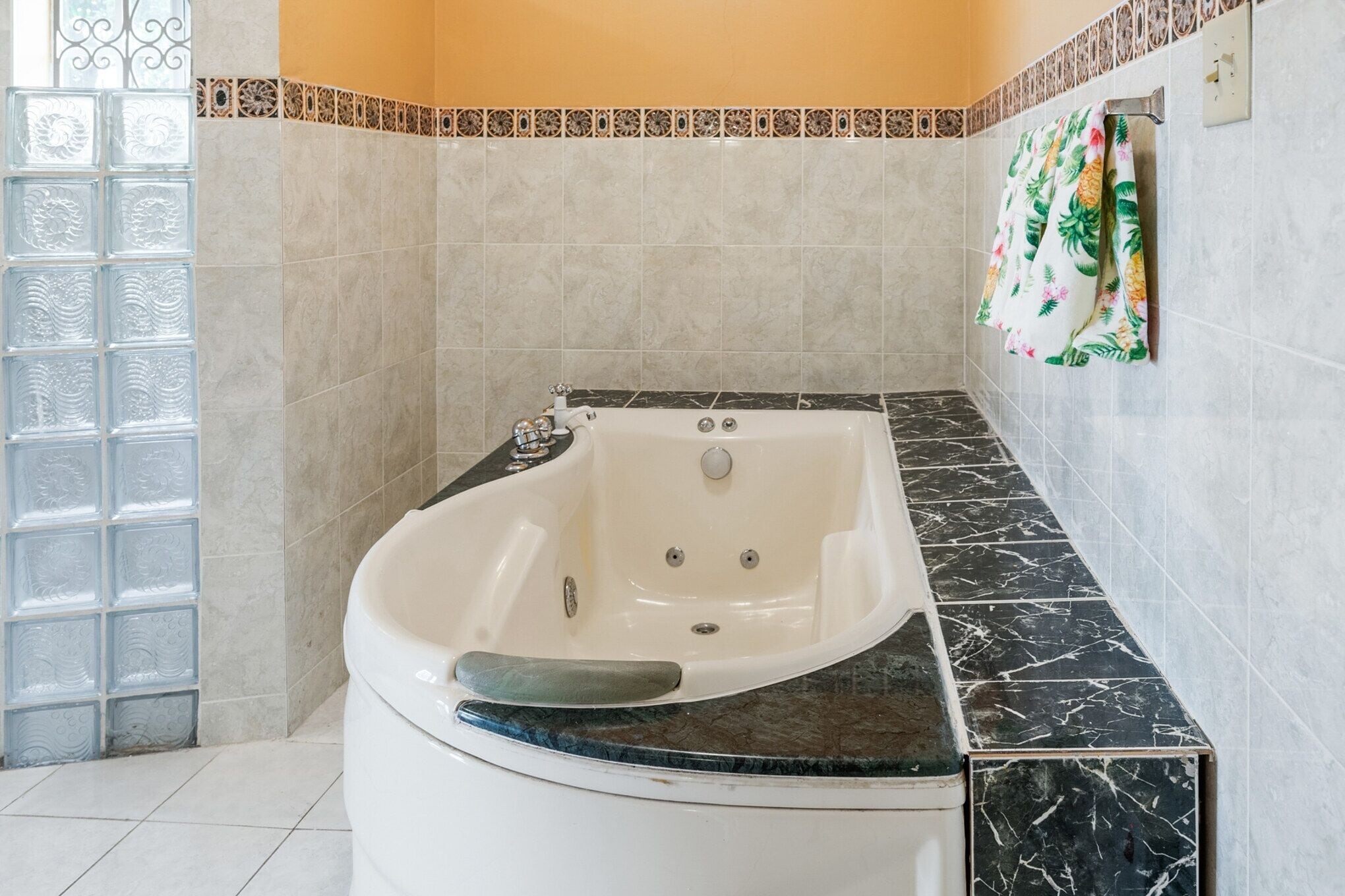 Een badkamer met een vrijstaand bad, betegelde wanden en een decoratieve douchehoek.