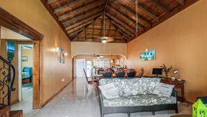 A spacious living area with a high wooden ceiling, a sofa with floral cushions, and a dining area in the background. - YanceyLargo- 4BR Villa Jacuzzi & Mountain Views by RedAwning (Montego Bay)