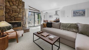 Un salon moderne avec un mur en pierre, un canapé, une table basse et une cheminée.