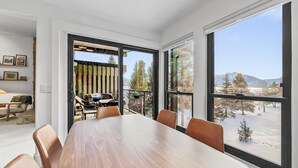 Une salle de conférence moderne, dotée d’une grande table en bois et de fauteuils en cuir, ainsi que de grandes fenêtres offrant une vue sur un paysage enneigé et des arbres.
