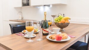 Ett frukostbord med croissanter, en flaska champagne, glas med apelsinjuice och en skål med frukt.