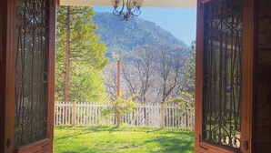 An open wooden door leading to a balcony with a view of a mountain and a white picket fence.