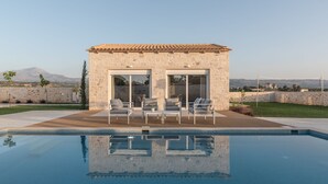 A stone building with a tiled roof, a swimming pool, and outdoor seating.