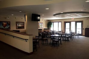 A spacious indoor area with a reception desk, multiple tables and chairs, large windows, and a flat-screen TV mounted on the wall. - Wonderful Home Away From Home - Free Night (Galena)
