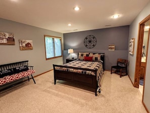A bedroom with a bed, a bench, a chair, a window, and wall decorations. - Wonderful Home Away From Home - Free Night (Galena)