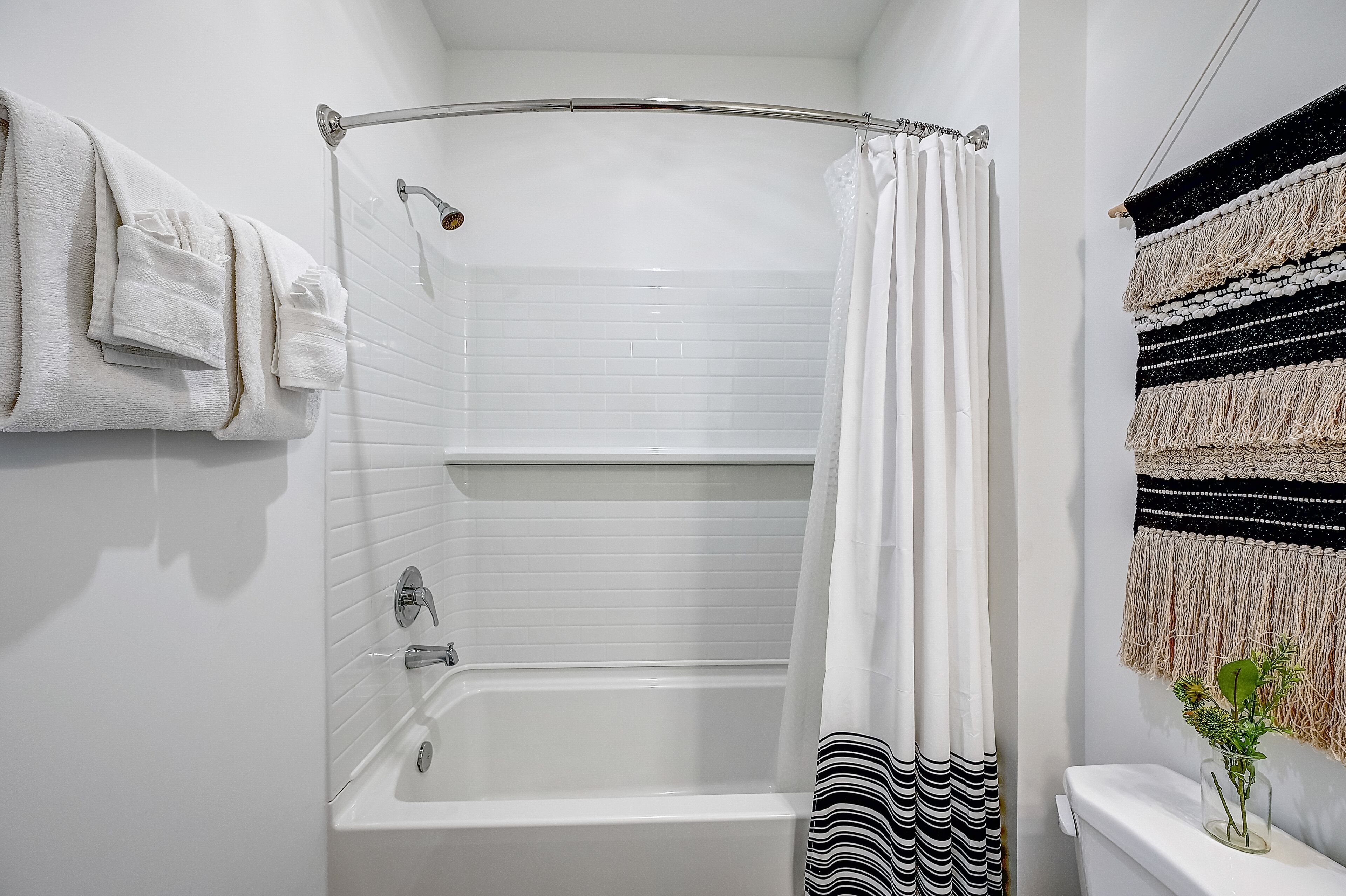 Ein Badezimmer mit einer weißen Badewanne, einer Duschvorhang und einem gestreiften Handtuch an der Wand.