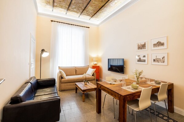 A cozy living room with a sofa, coffee table, and dining table with chairs.