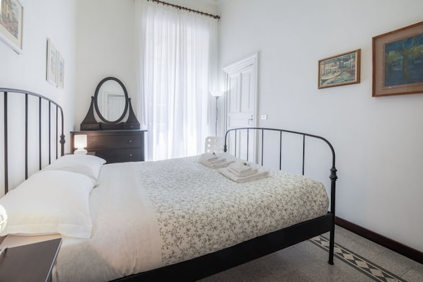 Un dormitorio con una cama, un aparador, un espejo y una puerta.