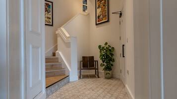 Un couloir avec un escalier, une chaise et une plante en pot.
