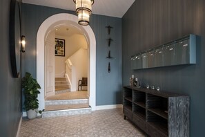 A hallway with a staircase, a wall-mounted shelf, and a potted plant.