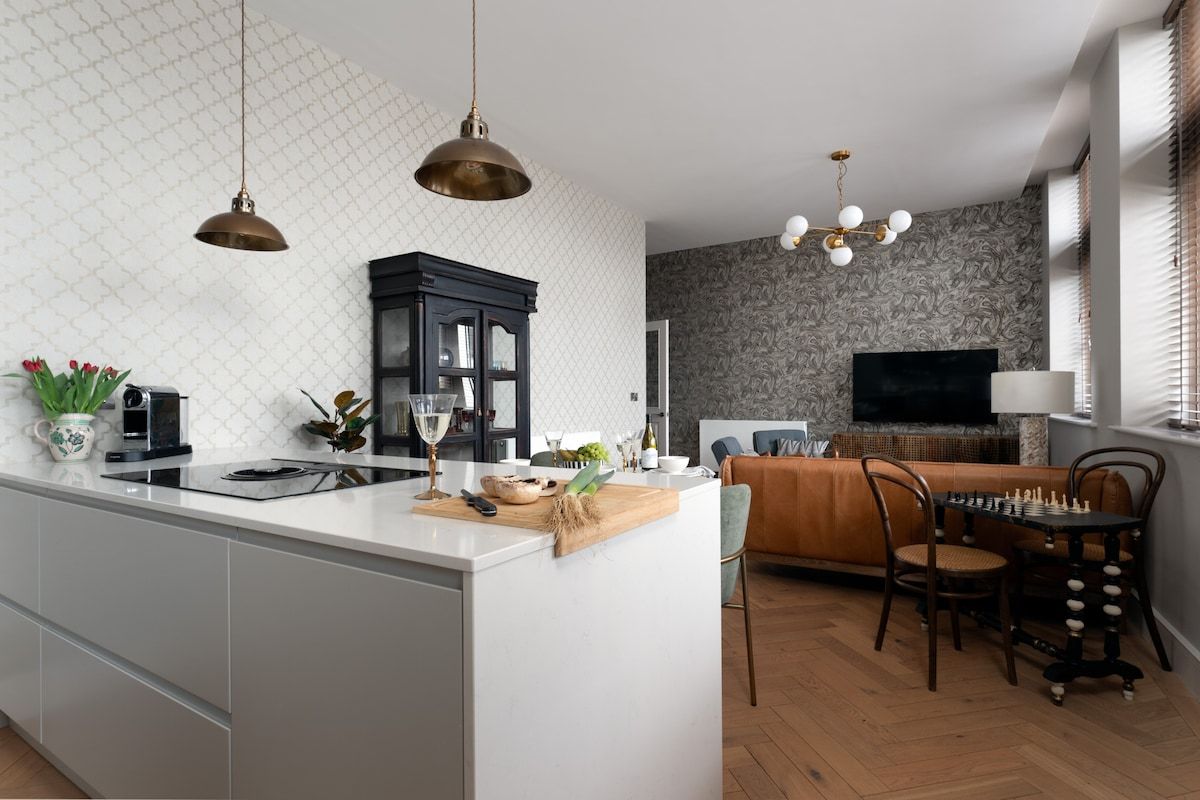 A modern kitchen with a central island, a dining area with a chessboard, and a living room with a TV.