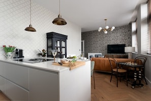Een moderne keuken met een centraal eiland, een eethoek met een schaakbord en een woonkamer met een televisie.