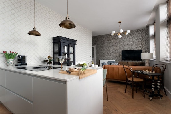 A modern kitchen with a central island, a dining area with a chessboard, and a living room with a TV.