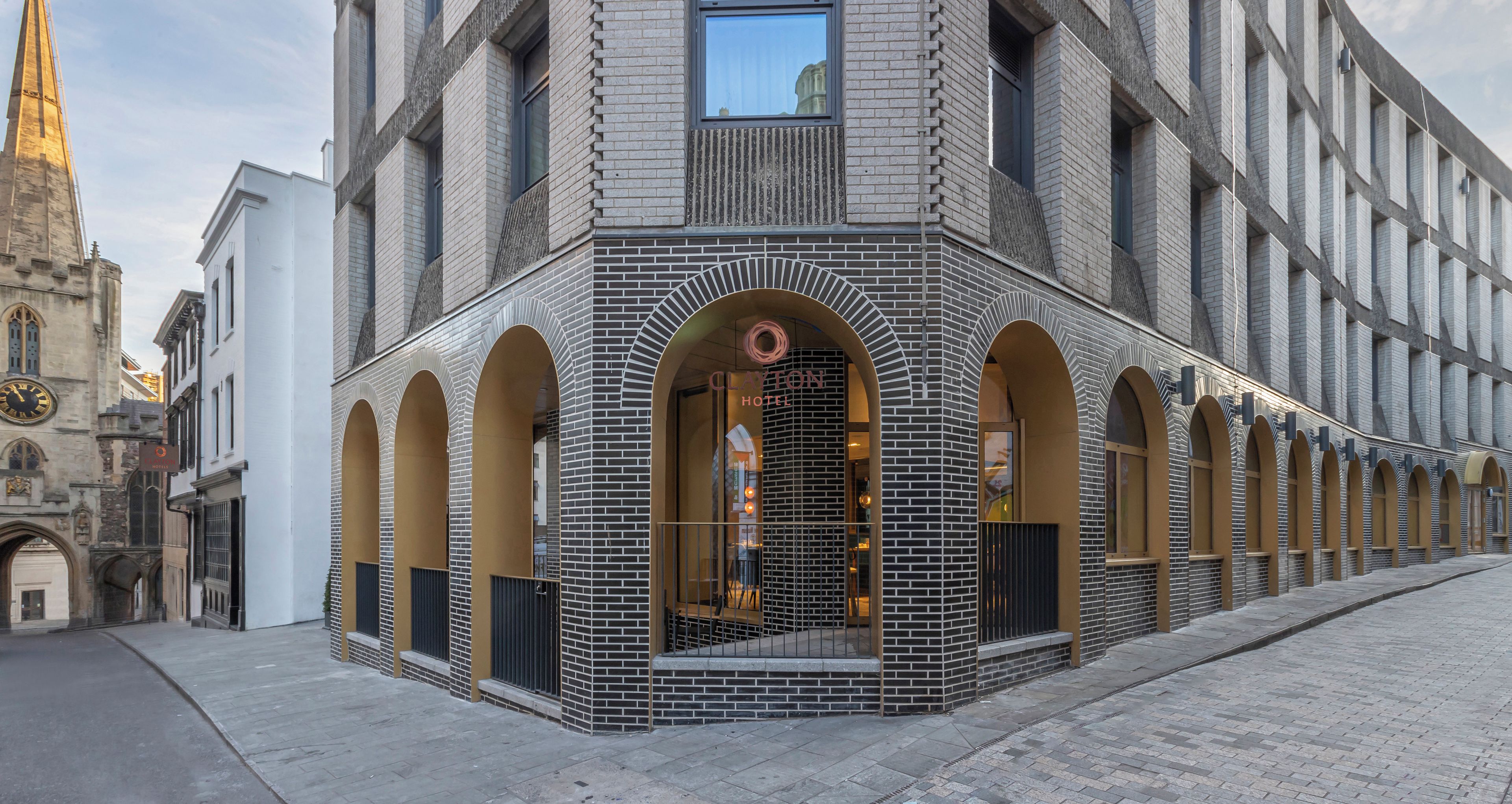 A hotel with a distinctive brick facade, arched windows, and a central entrance with a sign.