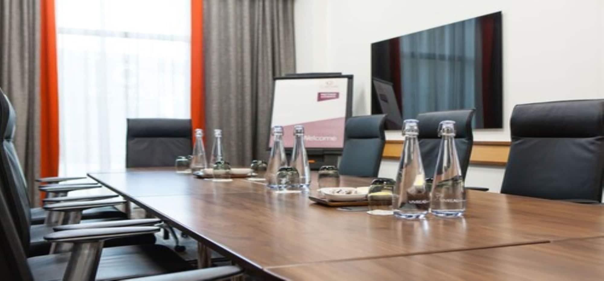 A conference room with a long table, chairs, and water bottles.