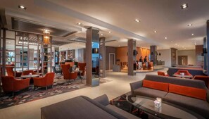 Een ruime lobby met moderne zitplaatsen, een receptie en een zichtbare trap.