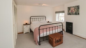 A bedroom with a bed, bedside tables, a window, a fireplace, and a wall-mounted TV.