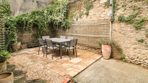 A patio with a table and chairs, surrounded by a stone wall and a wooden fence.