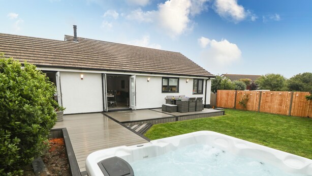A modern house with a hot tub, a deck, and a fenced backyard. - Bwthyn Eirlys (Cemaes Bay)