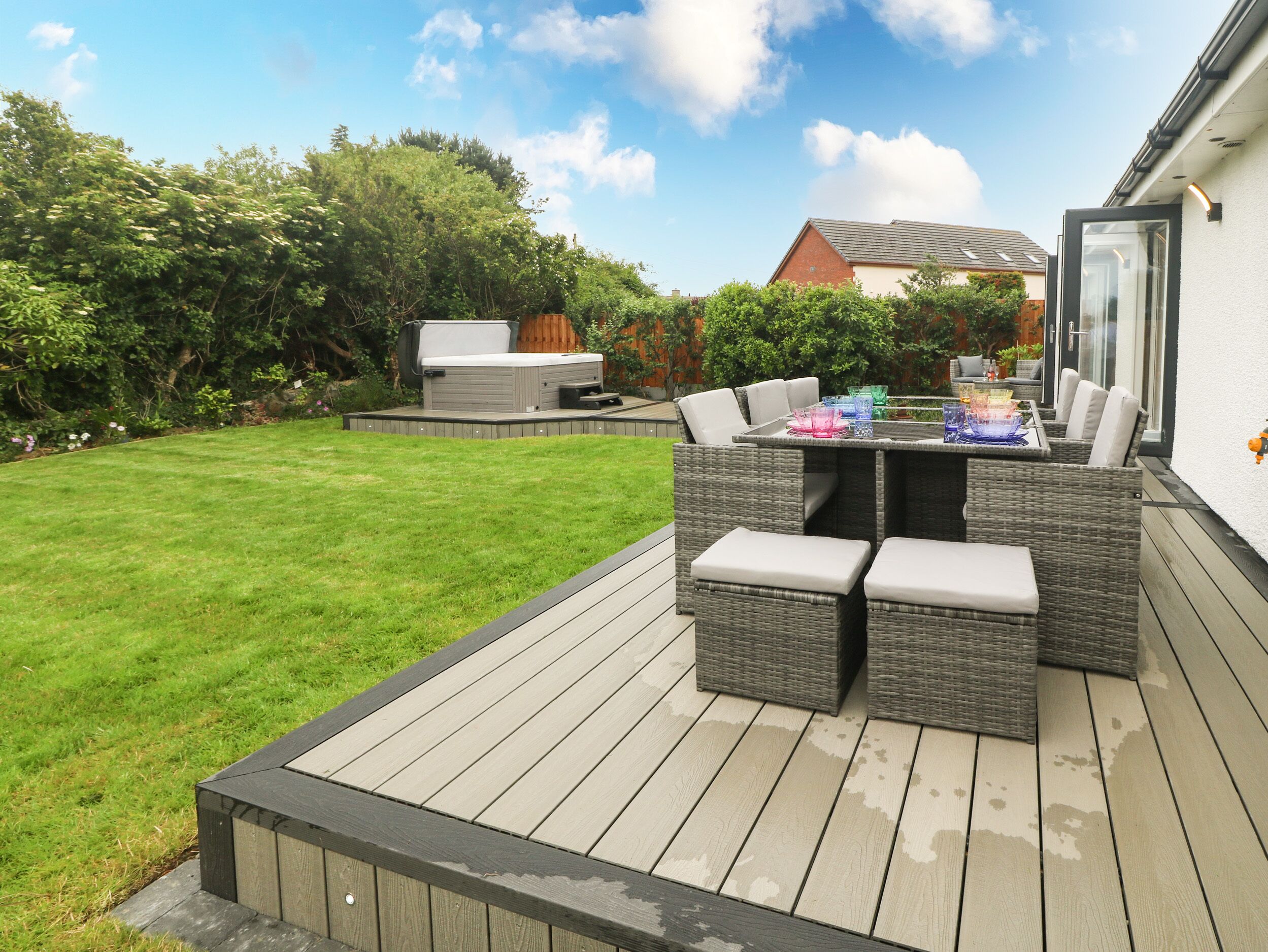 A deck with outdoor furniture, a barbecue, and a view of the backyard.