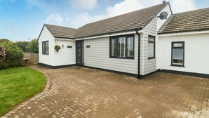 A two-story house with a paved driveway and a well-maintained lawn. - Bwthyn Eirlys (Cemaes Bay)