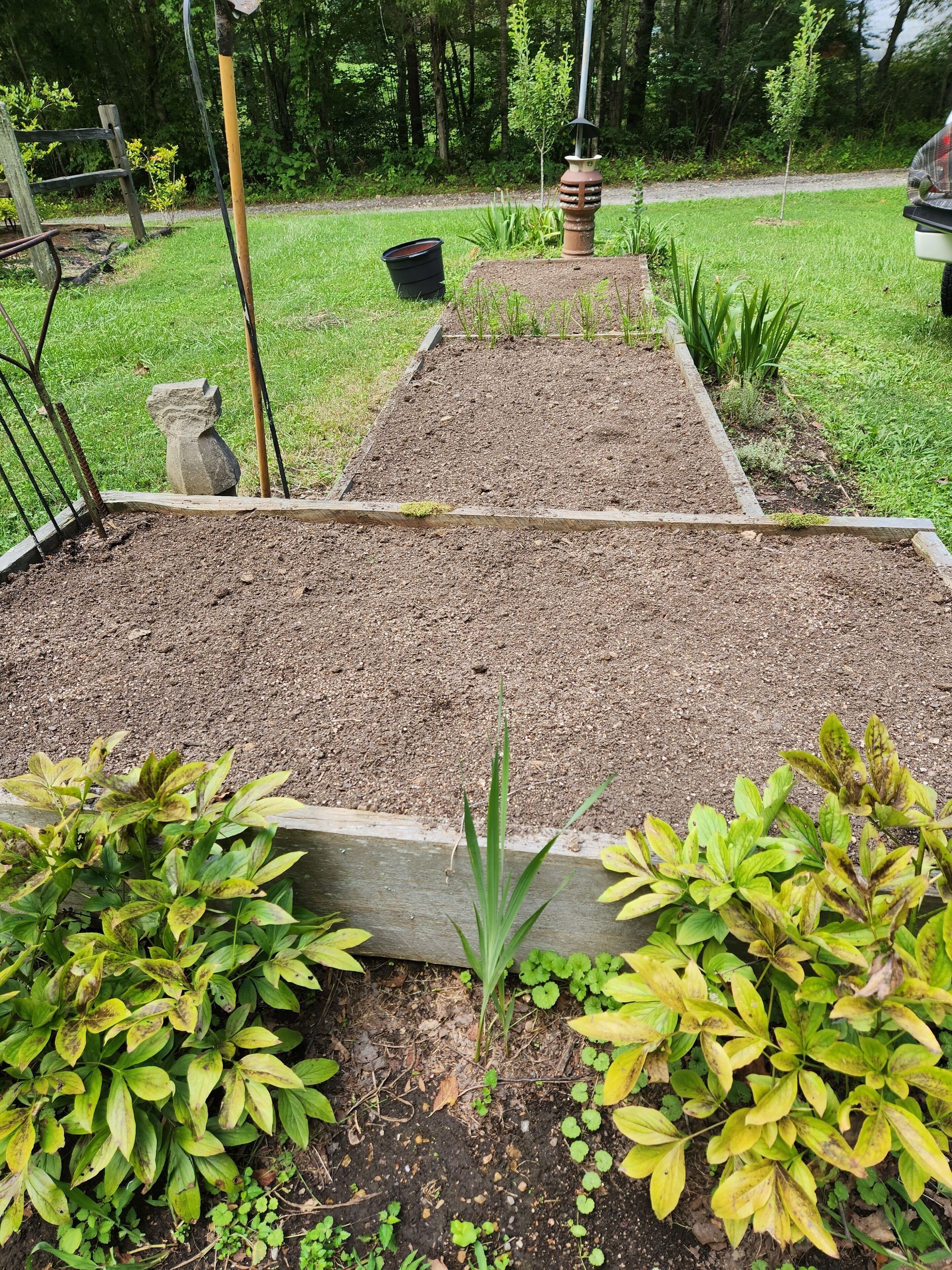 A garden with raised beds, a stone sculpture, and a wooden bench.