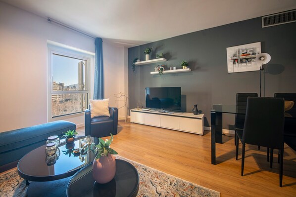 Een moderne woonkamer met een bank, televisie en een eethoek.