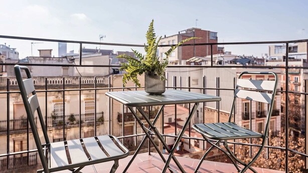 Un balcó amb dues cadires de metall, una taula petita i una planta en test.