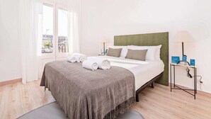 Habitació d'hotel amb un llit, dues taules de nit, una finestra amb cortines i vista a la ciutat.
