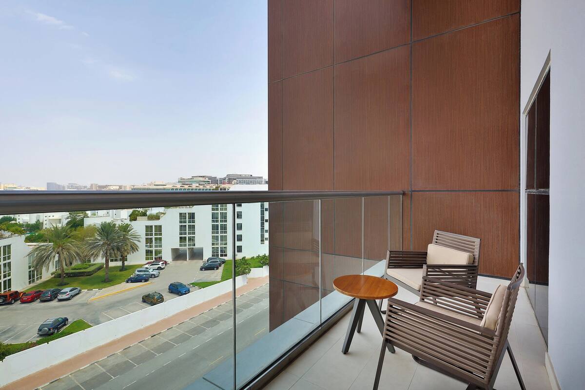 A balcony with a view of a parking lot and buildings.