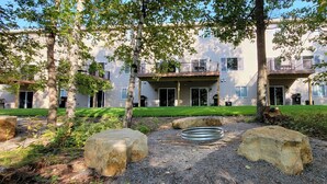 A residential building with multiple balconies, a well-maintained lawn, and a fire pit area. - The Blue Ox on Gull, 5 Bed 5 Bath Resort Home, Sleeps 17 with Boat Slip on Gull Lake (Lake Shore)
